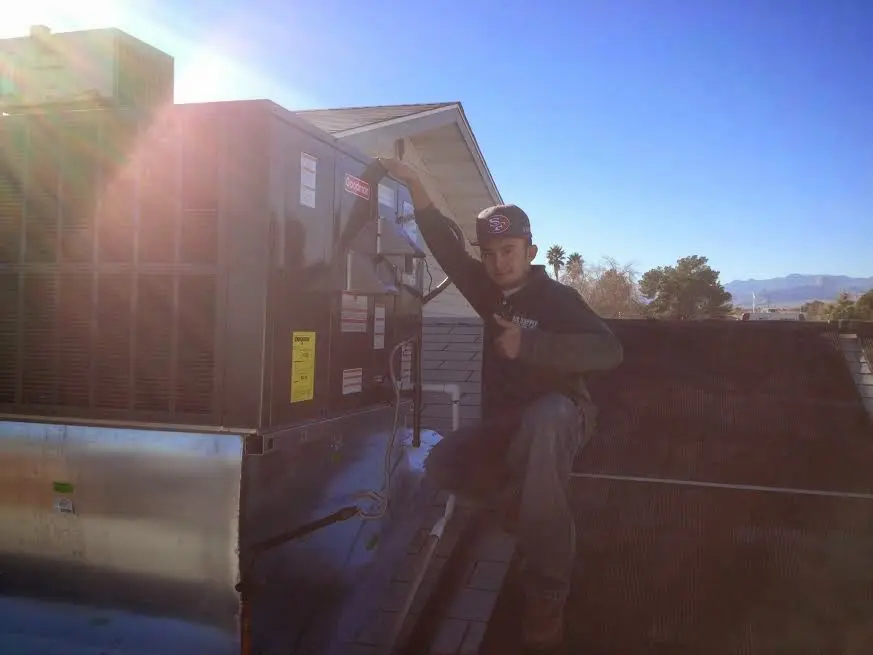 HVAC technician performing AC Tune-Up on a rooftop unit in New Bedford